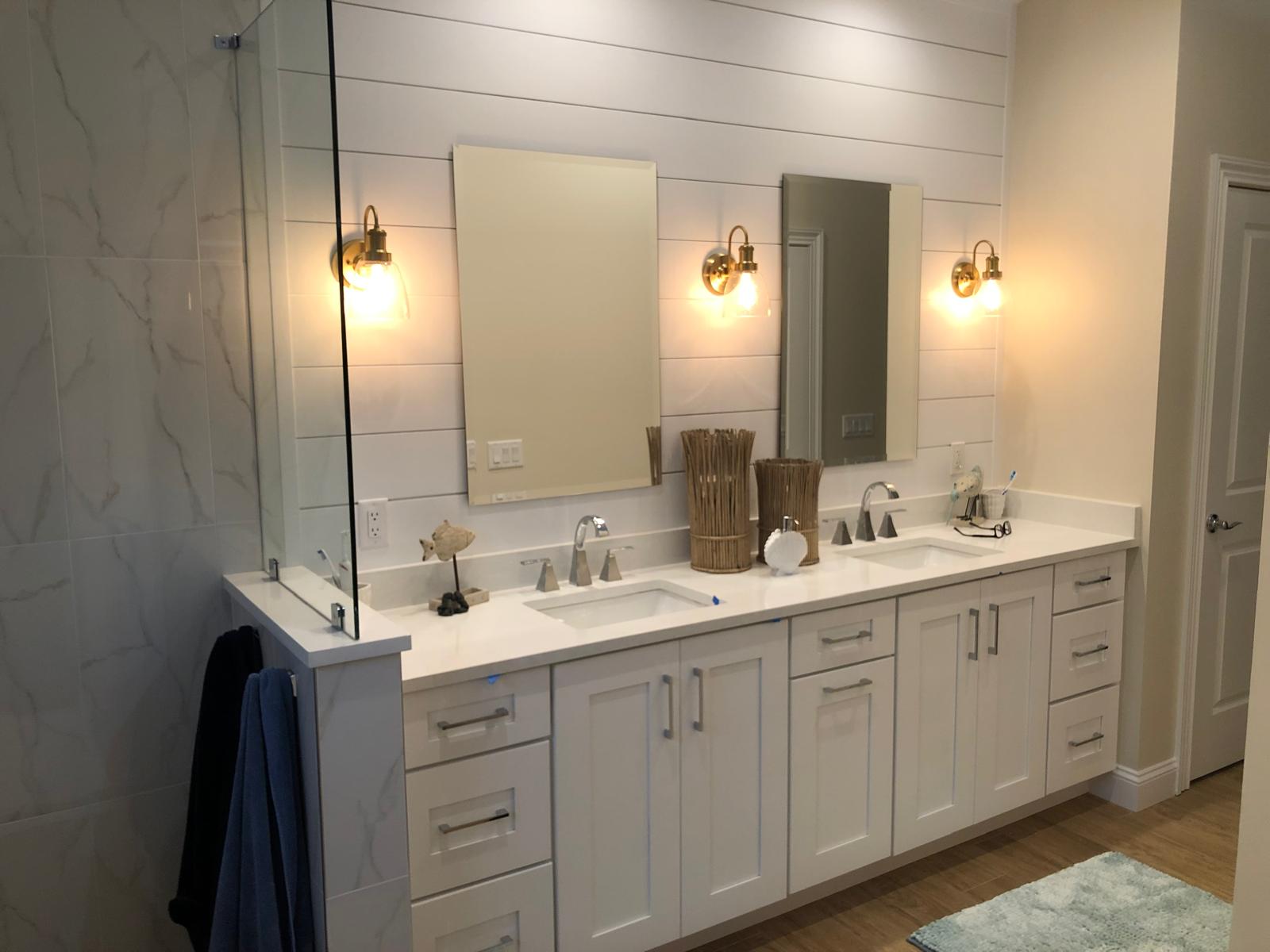 Finished bathroom with double vanity, mirrors, sconces, glass shower, and modern finishes