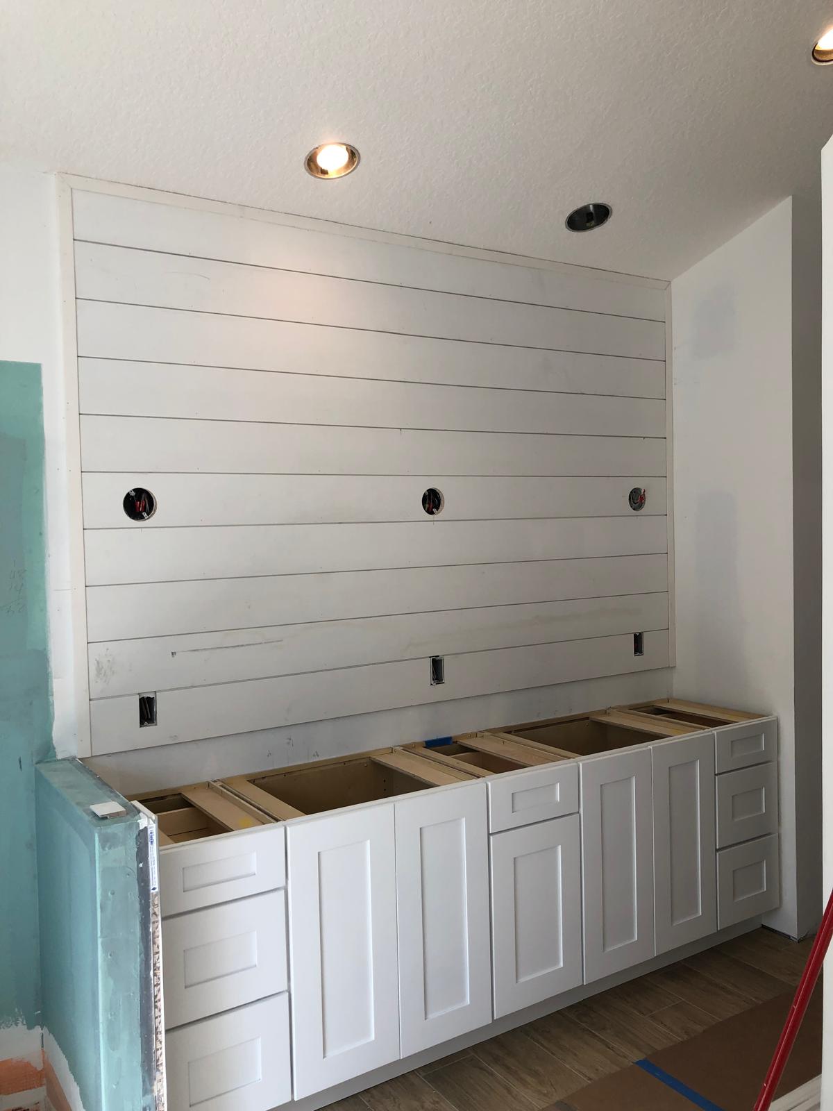 Bathroom before final finishes with vanity cabinets and shiplap wall installed